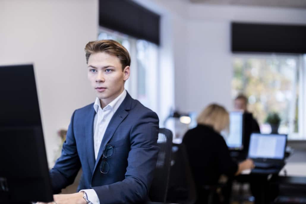 Ung medarbejder arbejder koncentreret foran skærmen i vores åbne inkassofirma.