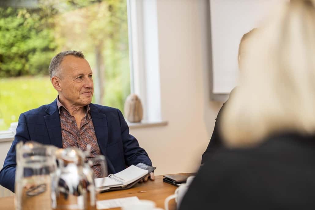 Ældre mandlig rådgiver i dialog med klienter om retslig inkasso over bordet.