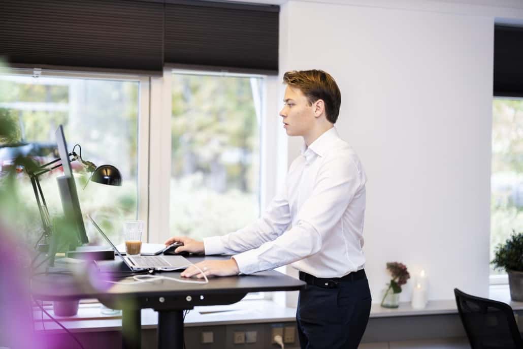Mand arbejder effektivt med inkasso service ved sit hævesænkebord.
